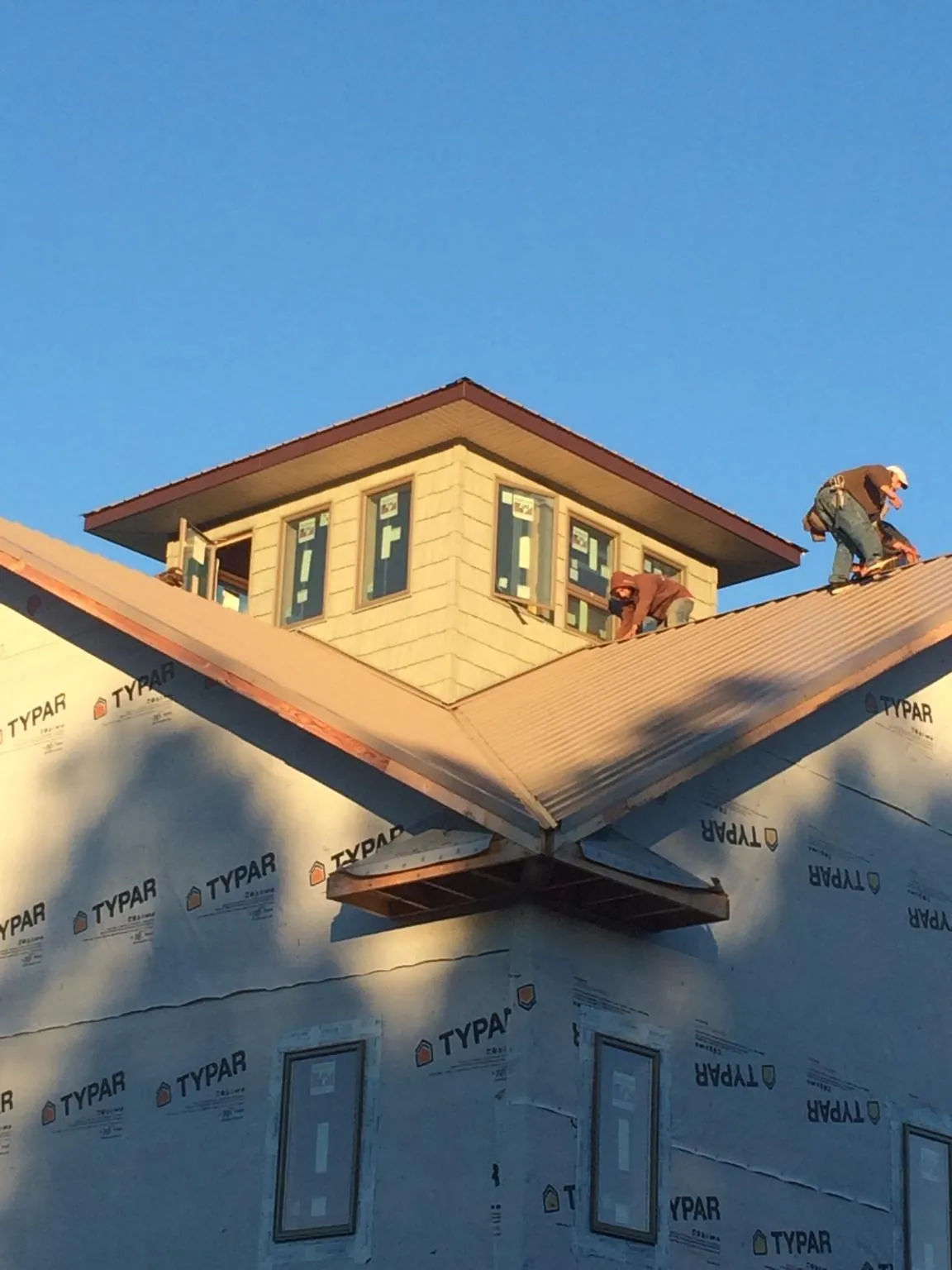 Roofers working around a rooftop cupola on a new metal roof at sunset — Roof Waterproofing in Lake Mills by Roofing Brothers